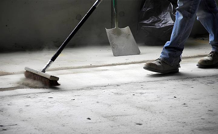 Mitarbeiter fegt den Boden auf der Baustelle